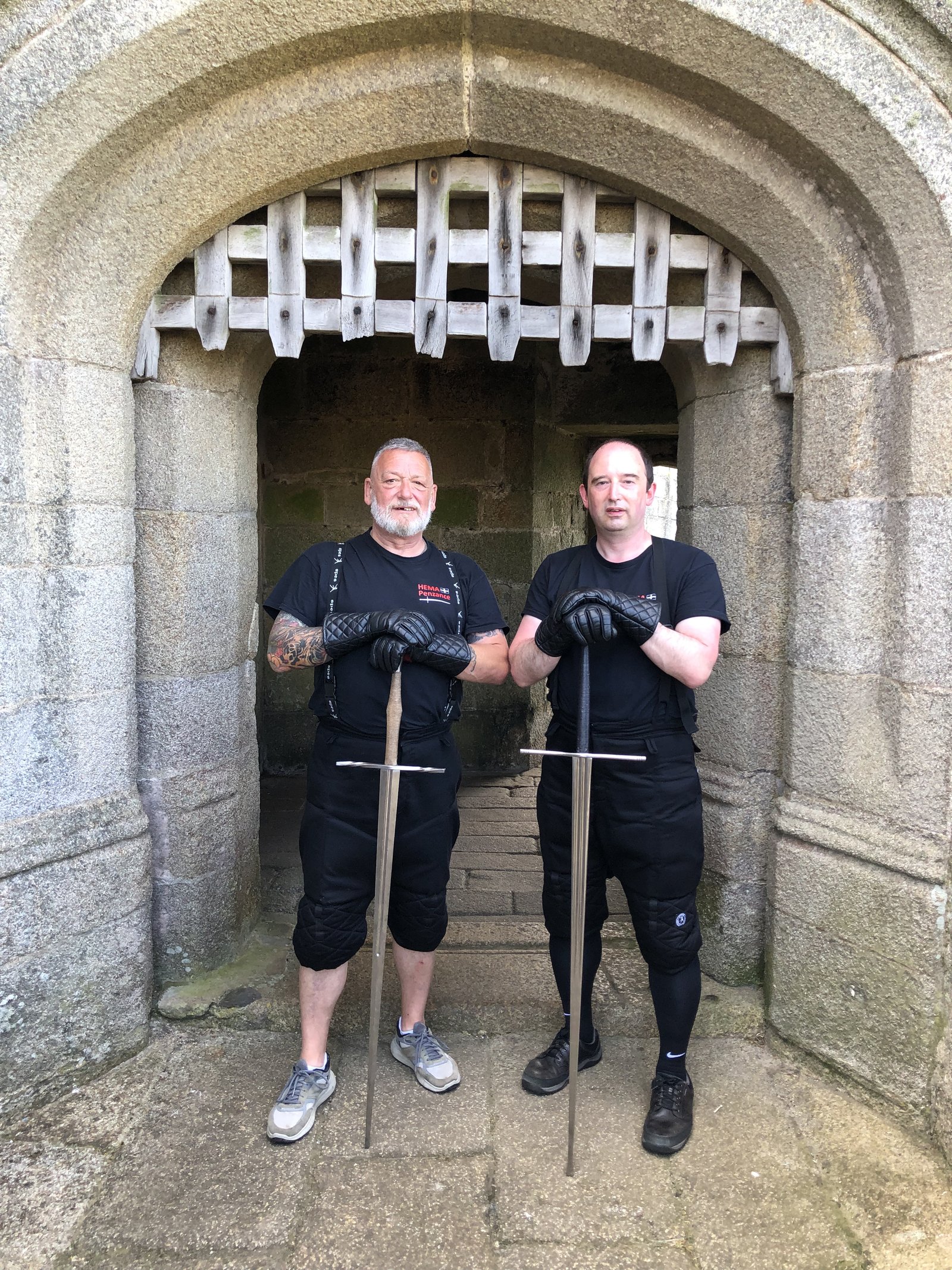 Two HEMA Penzance members with longswords at a Pendennis Castle gateway