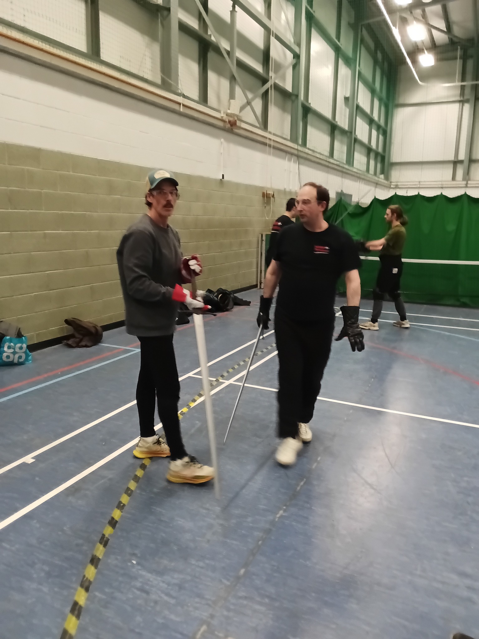 Members chatting between drills with swords in hand